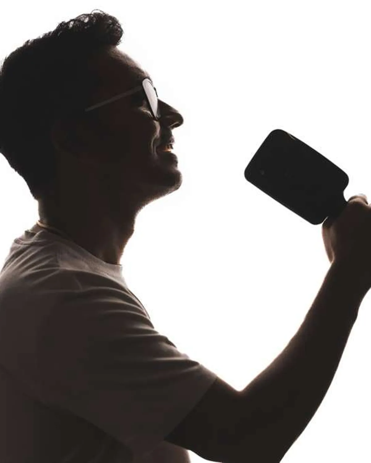 Sai Shankar of The Untitled Band, silhouetted in profile mid-song with a microphone.